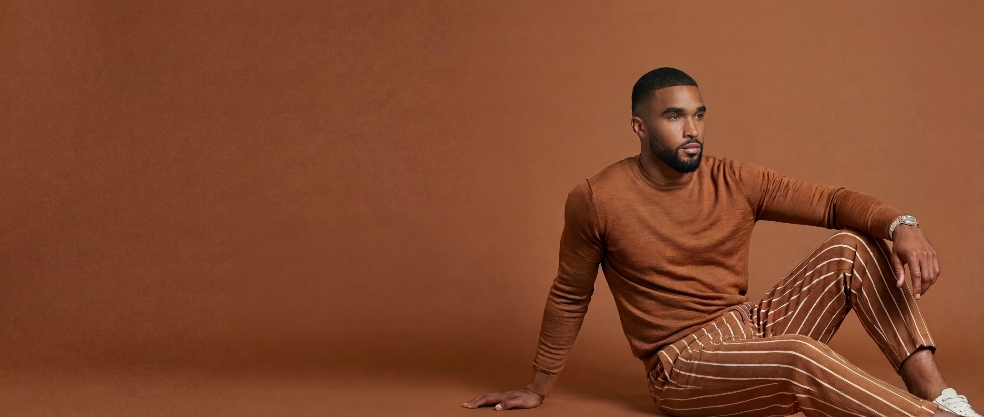A Black male estetiq model seating confidently
